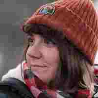 Caucasian woman (me) with brown hair wearing an orange hat looks away from the camera to the left.